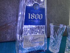 a bottle of liquor sitting next to two glasses on a blue tablecloth covered table