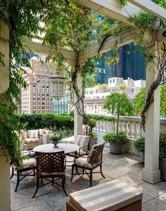 an outdoor dining area with chairs and tables on the patio, surrounded by greenery