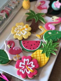 some decorated cookies are on a plate with pink and yellow flowers, pineapples, watermelon