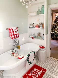 a white bath tub sitting next to a christmas tree in a bathroom under a chandelier