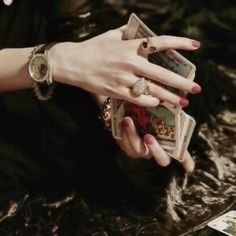 a woman's hand holding several cards in her left hand and two diamonds on the other