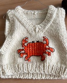 a knitted sweater with an orange crab on it