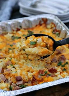 a casserole dish with ham and cheese being lifted by a spatula over it