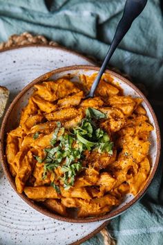 a bowl filled with pasta and garnished with parsley on a blue towel