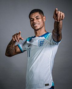 a soccer player poses for a portrait with his arms in the air and one hand up