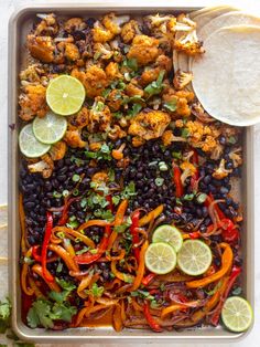 a tray filled with chicken, black beans and limes