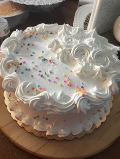 a white frosted cake with sprinkles on it sitting on a table