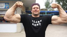 a man flexing his muscles in front of a building