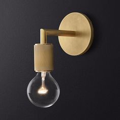 a light bulb mounted on the side of a black wall with a gold colored metal arm