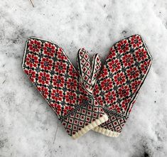 a pair of red and white mittens sitting on top of snow covered ground