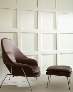 an egg chair and ottoman in front of a white wall