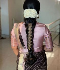 a woman with long black hair wearing a pink sari and flower in her hair