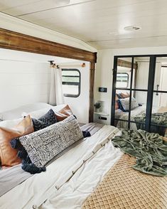 a bed in a room with pillows and blankets on top of it next to a mirror