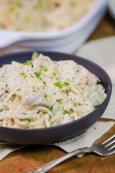 a bowl filled with chicken salad on top of a wooden table next to a fork