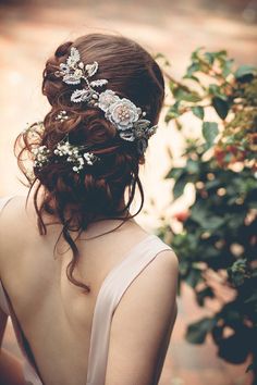 the back of a woman's head with flowers in her hair, wearing a white dress