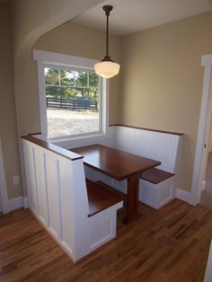 an empty room with a wooden table and bench in it, next to a window