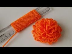 an orange crochet flower next to a measuring ruler