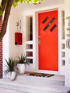 a bright red door with two planters on the steps