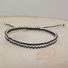 a pair of black and white braided bracelets sitting on top of a piece of wood