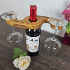 there is a wine glass holder on the table next to two wine glasses and a flower