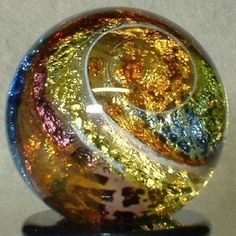 a colorful glass ball sitting on top of a black stand next to a white wall