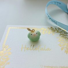 a small green bird charm sitting on top of a card