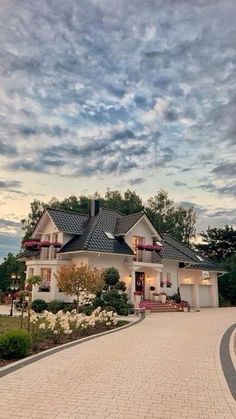 a large white house sitting on top of a lush green field under a cloudy sky