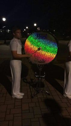 two men standing next to each other in front of a rainbow colored ball on a stand