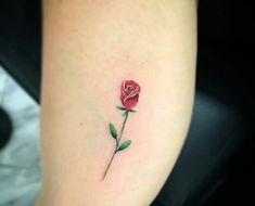 a single rose tattoo on the left side of the arm, with green leaves around it