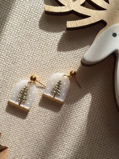 a pair of white earrings sitting on top of a table next to a wooden clock