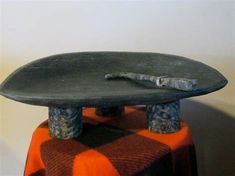 a skateboard sitting on top of a table with an orange and black checkered blanket