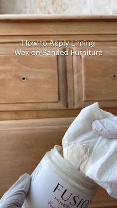 a person holding a jar of wax on top of a wooden dresser with the words how to apply luminous wax on sanded furniture