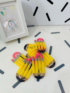 some yellow pencils are sitting on a table next to a white frame and a painting