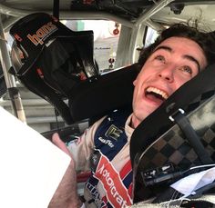 a man with his mouth wide open sitting in the back of a car and wearing a helmet