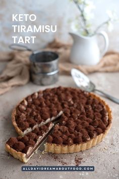 a chocolate tart on a table with a piece missing from it and the text keto tiramiu tart overlay