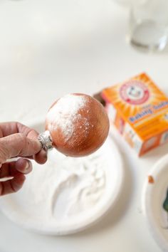 a person is holding an ornament in front of a plate with powdered sugar on it