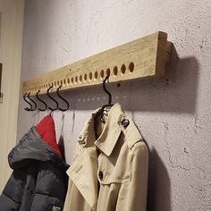 two coats hanging on a coat rack in front of a white wall and another coat hanger