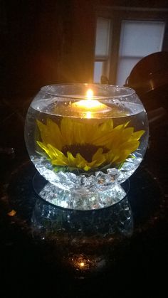 a sunflower in a glass bowl on a table