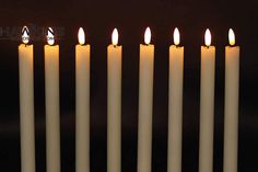 seven lit candles in front of a black background with the word hanukka's on it