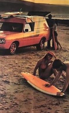 two surfers are sitting on the beach with their surfboards in front of an suv