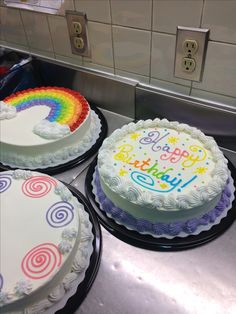 three birthday cakes with rainbow frosting sitting on top of a counter next to each other