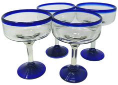 four wine glasses sitting next to each other on top of a white surface with blue rims