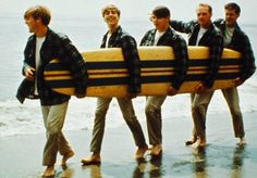 four men walking on the beach with their surfboards