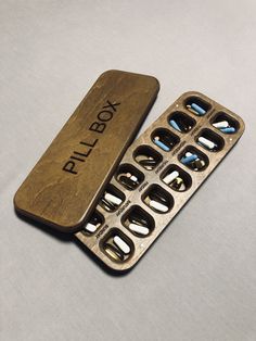 a wooden pill box sitting on top of a white table next to an empty bottle opener