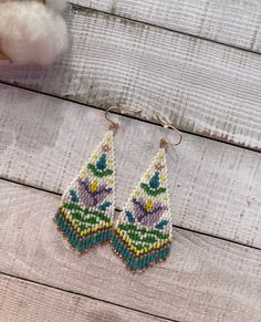 two pairs of beaded earrings on top of a wooden table