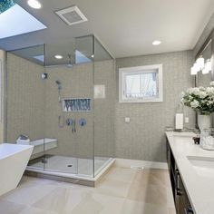 a large bathroom with a walk in shower next to a bathtub and sink under a skylight