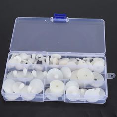 a plastic container filled with white candles on top of a black table next to a pair of scissors