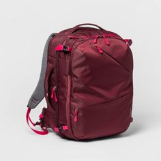 a maroon backpack with pink handles and zippers on the front, sitting against a white background