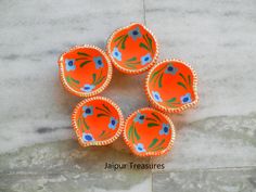 four orange bowls with blue flowers on them sitting on a marble counter top in front of a tile floor