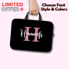 a woman's hand holding a black and pink bag with the letter h on it